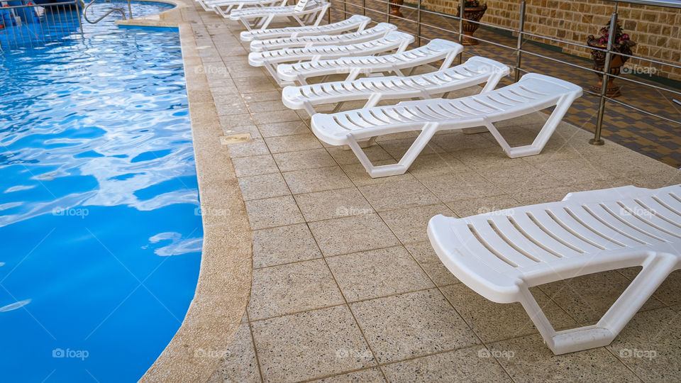 Row of free sunbeds at the swimming pool in a touristic resort.