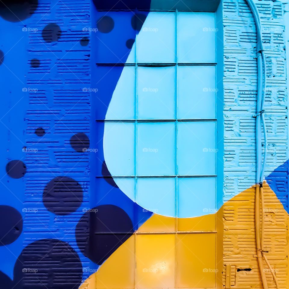 Artistically painted exterior wall and window in blues and yellow.