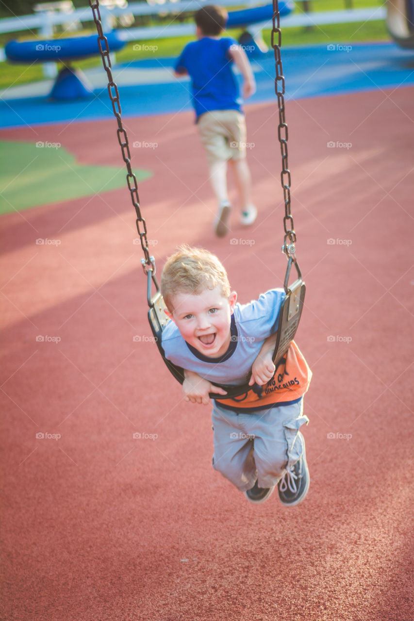 Young Boy Playing in a Swing at a Playground 2