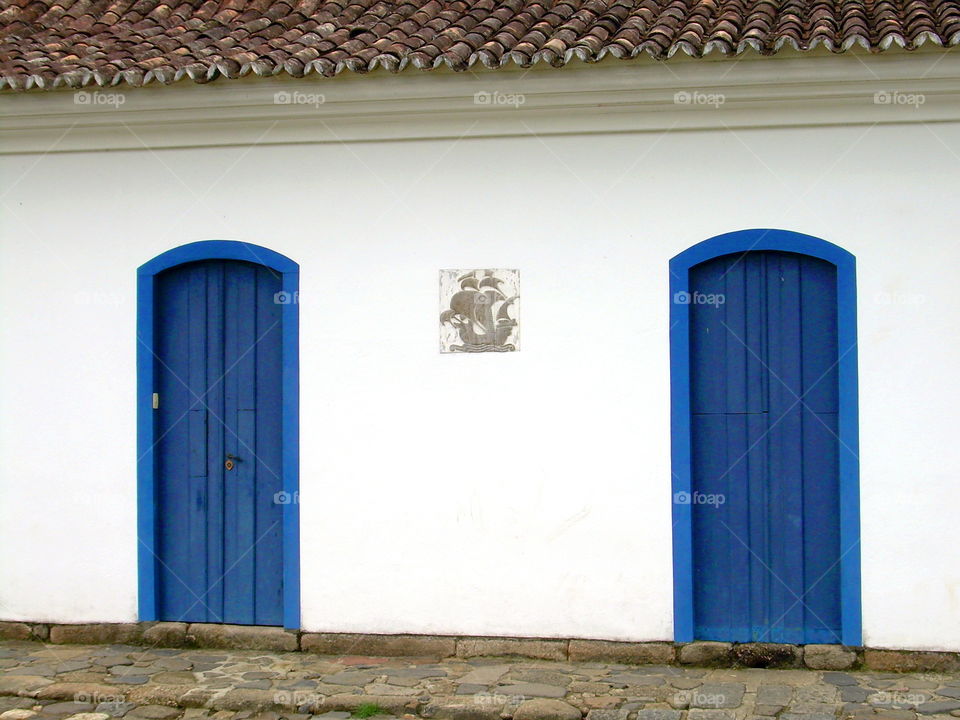 blue doors in white wall with a ship colonial house bungalow in Parati Brazil