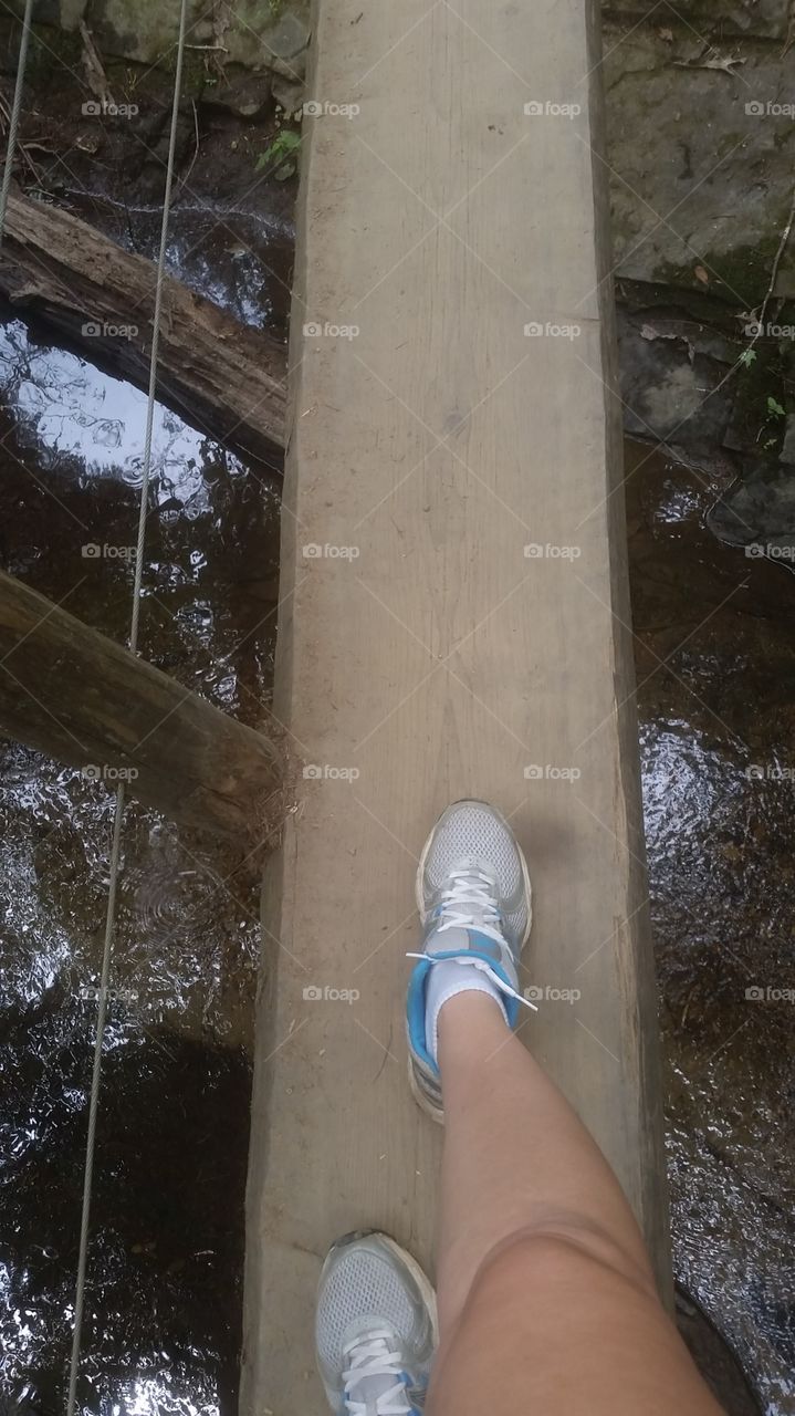 Walking across a thin narrow bridge on a hike in the forest