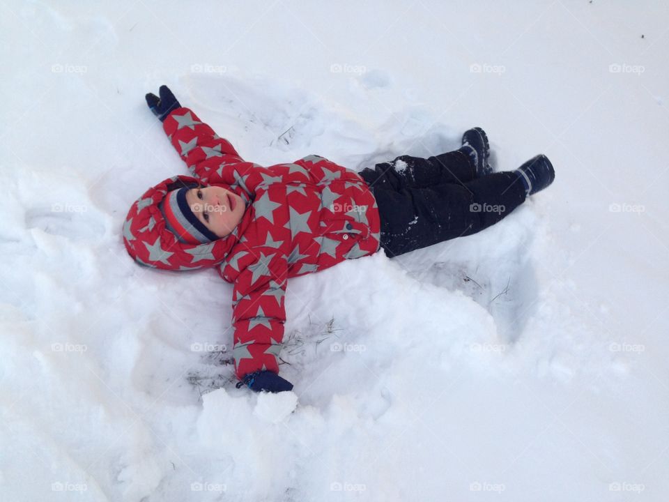 Three-year-old boy making a snow angel.