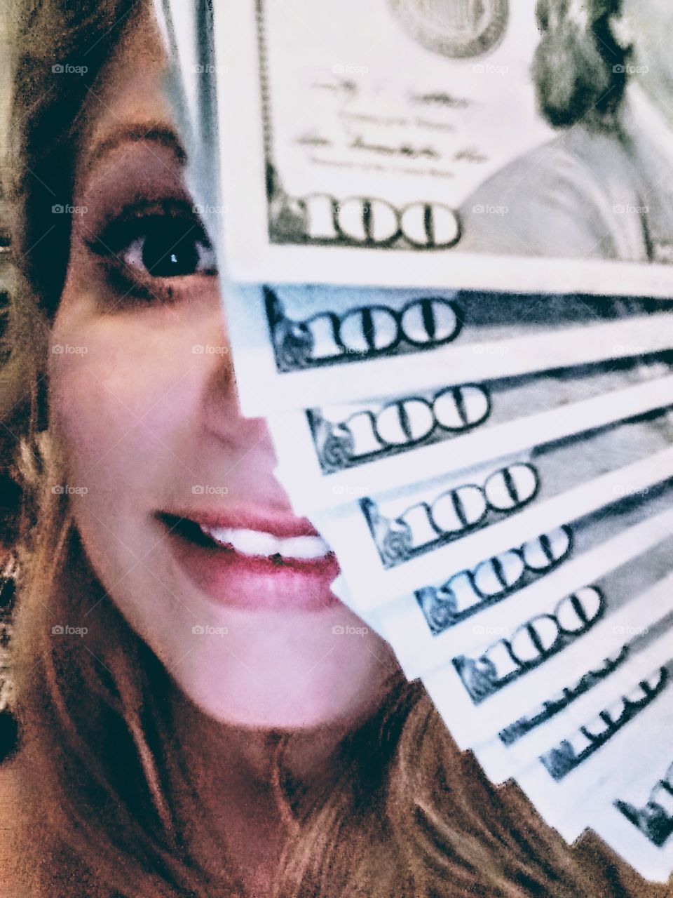 young woman taking a selfie with a stack of hundred dollar bills