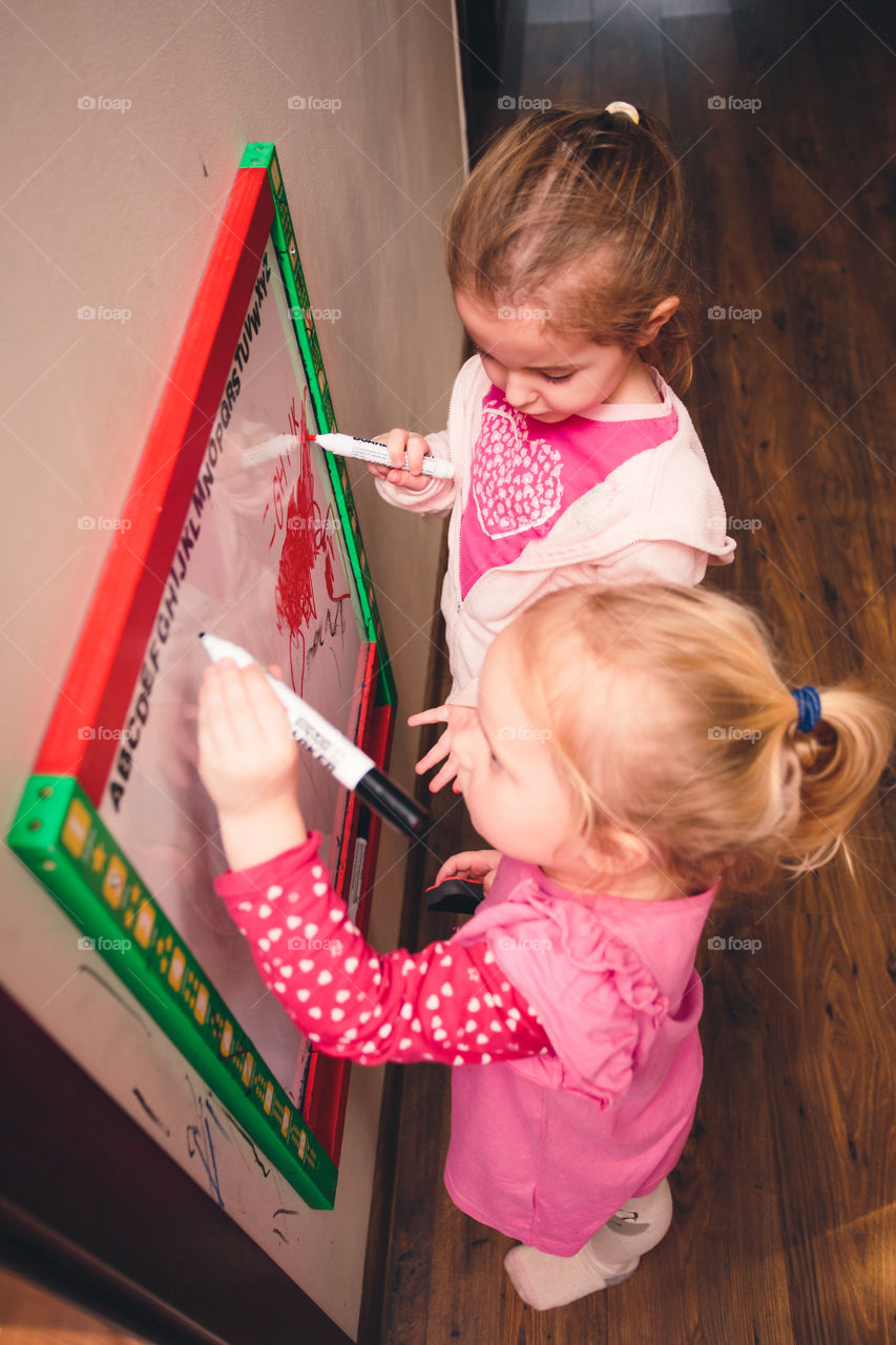 Children drawing a pictures learning a letters playing together using whiteboard and markers