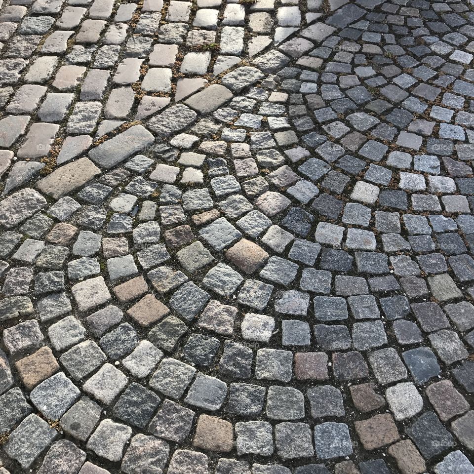 Curved and straight laid cobblestones seen in the morning light.