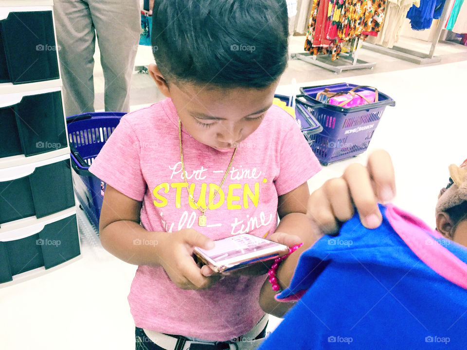 A boy using phone at the mall