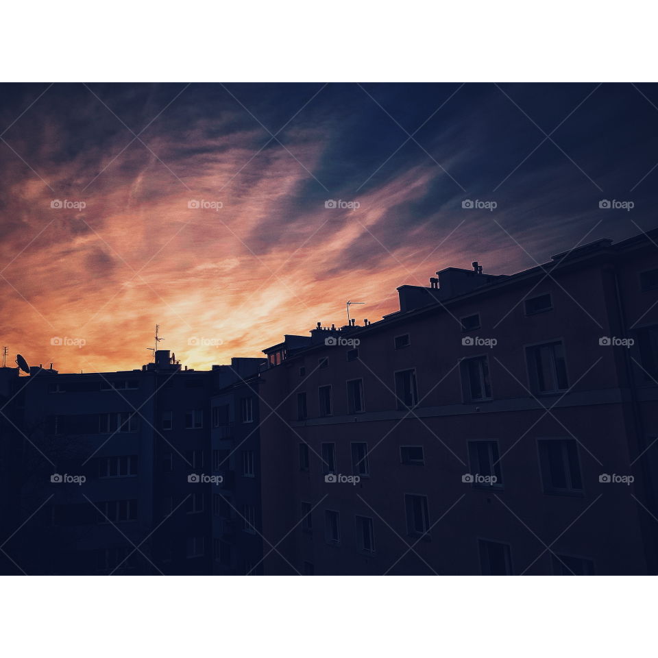 Sunrise silhouette of buildings and rooftop with dramatic sky in Warsaw.