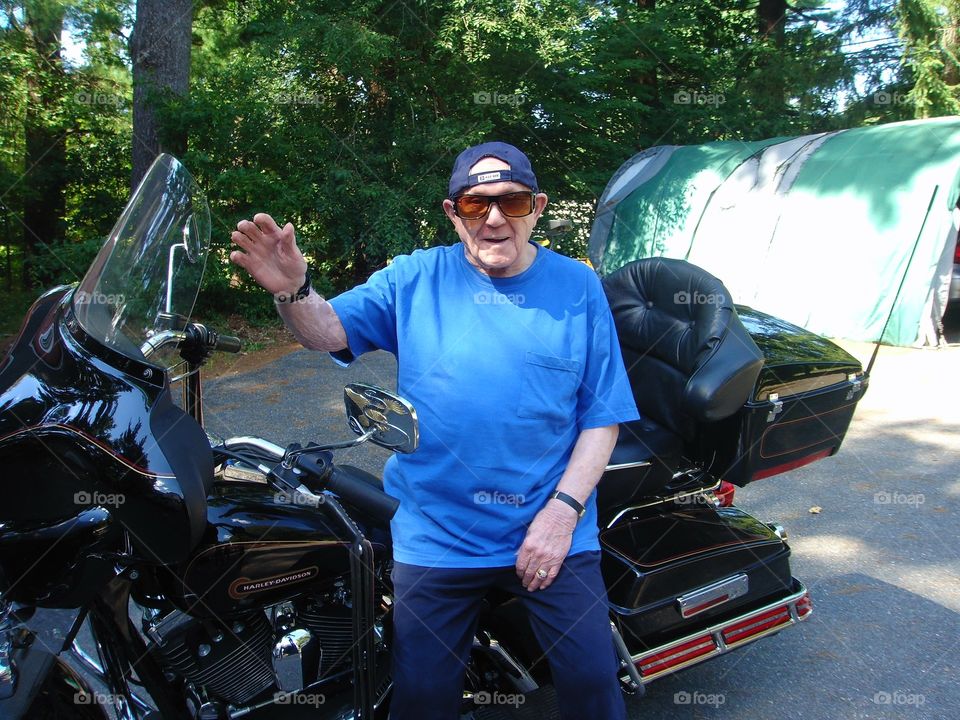 Senior man sitting on motorcycle, 93 years old. Waving.