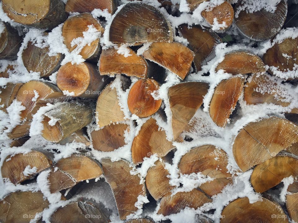 Pile of cut firewoods covered in snow