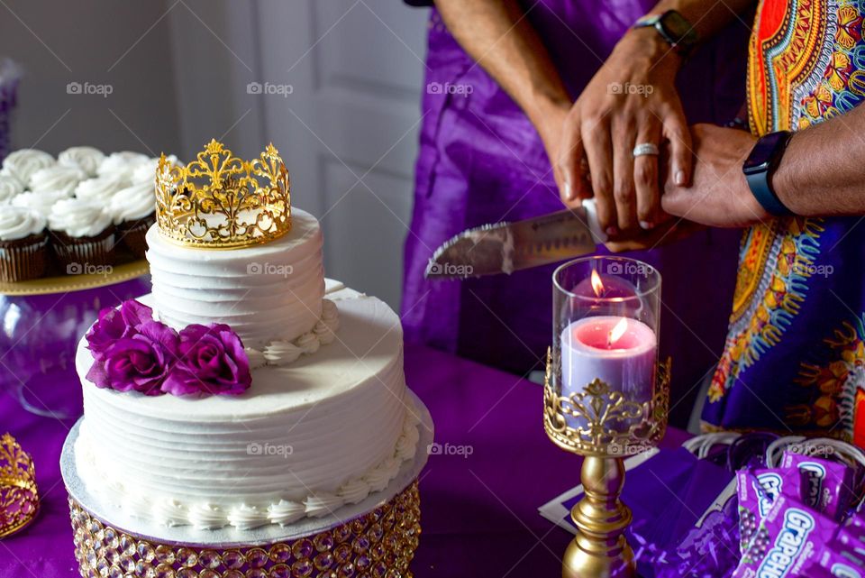 A couple holding hands in front of a wedding cake in the color of royalty 