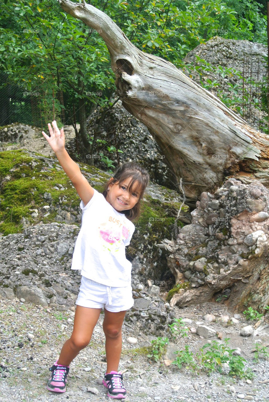 Happy girl standing near tree trunk