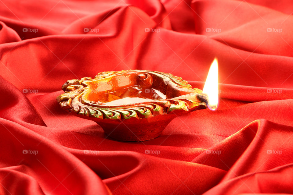 Beautiful traditional handmade Diwali diya oil lamp on red satin background