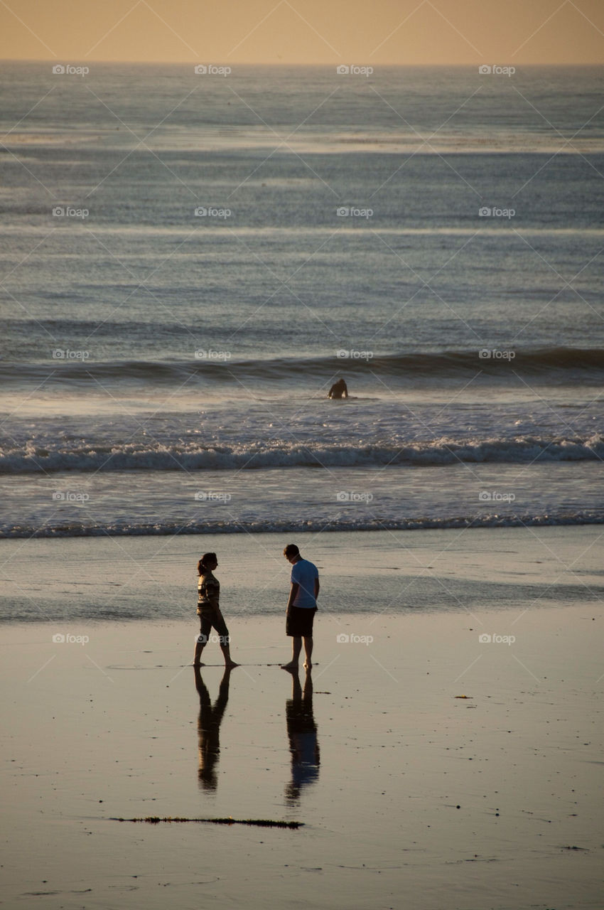 Man and woman walking on the beach at sunset