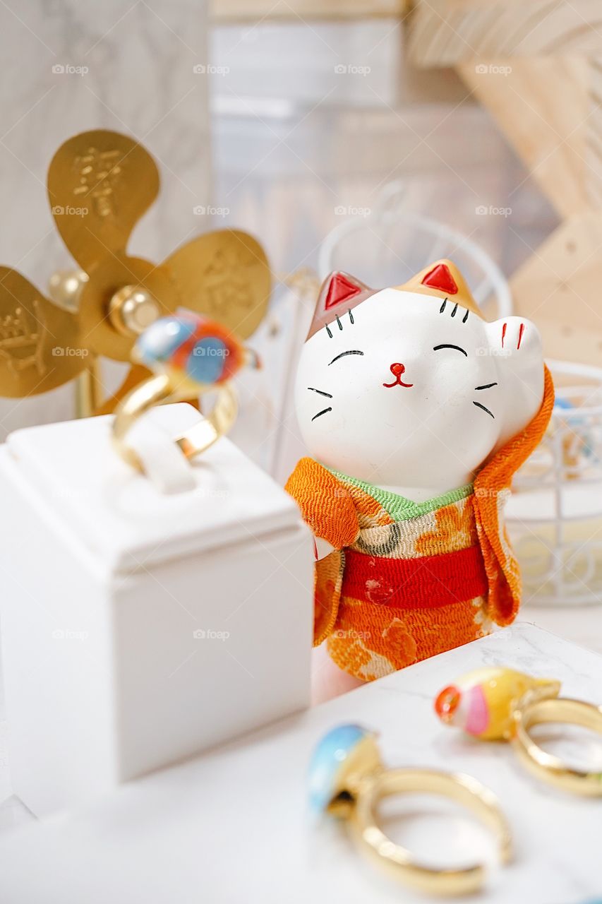 Welcoming cat or maneki neko in Japanese. A cute beckoning cat is wearing an orange Japanese traditional kimono. Japanese believes this cat will bring good fortune and business success.