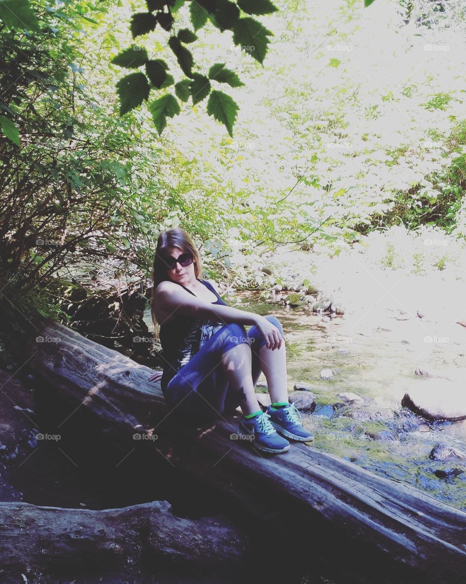 Portrait of woman sitting on tree trunk