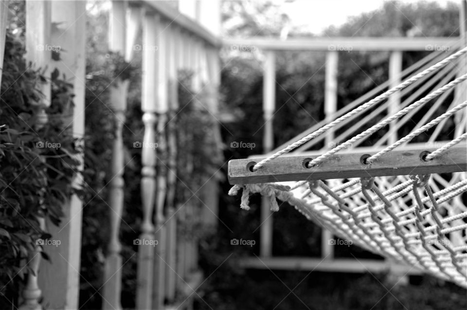 Black and white image of a hammock and railing 