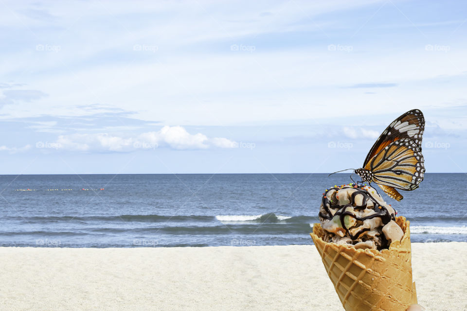 Orange Butterfly on Delicious ice cream Background sea and the bright sky in summer.