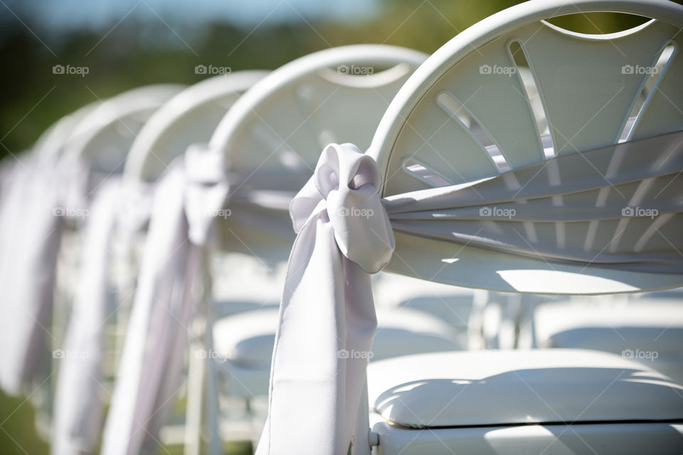 White wedding ceremony chairs with white ribbons and bows