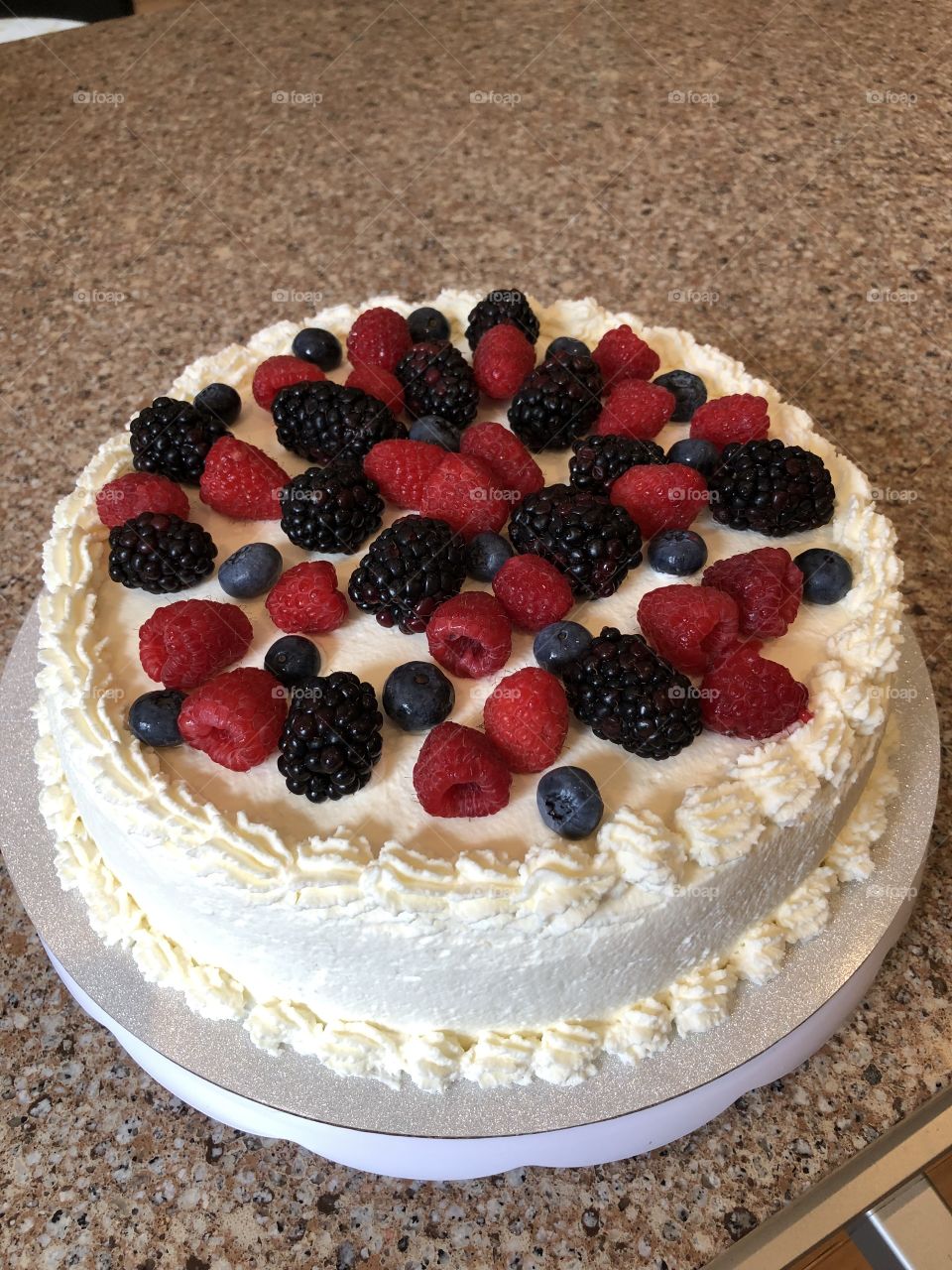 A beautiful, delicious, homemade whipped cream icing, vanilla "tres leches" Mexican cake with sweet raspberries, blueberries, and blackberries on top. 