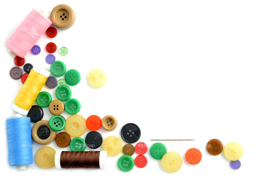 Colorful buttons and spools over white background