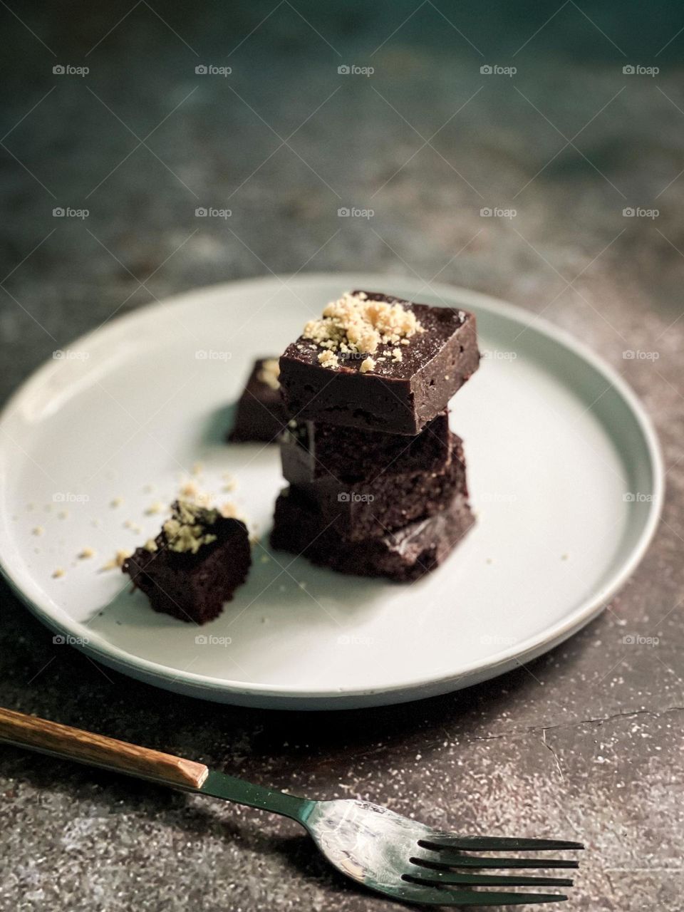 Brownies tower on a white plate on top of a stone table