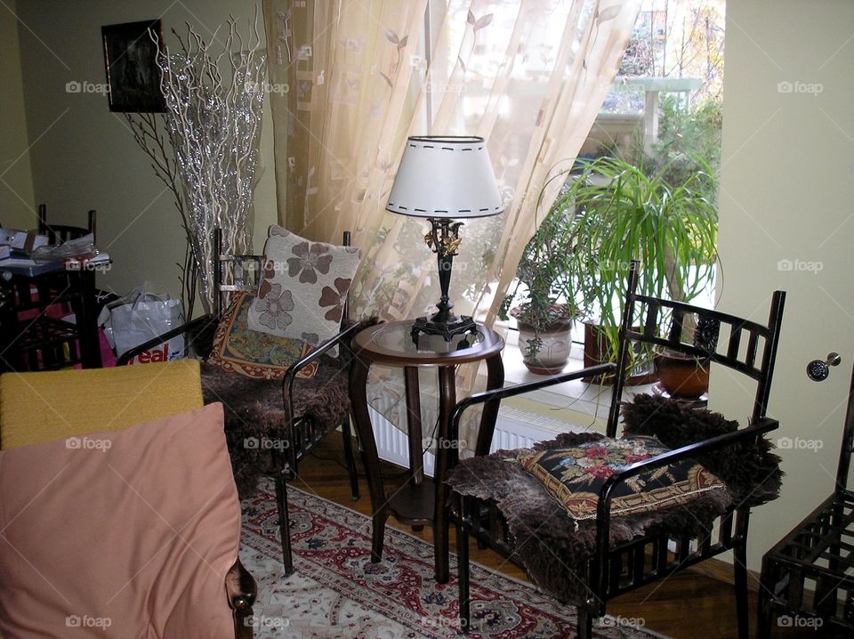 Interior design of a living room with beaten metal furniture and a lamp on the table at the window