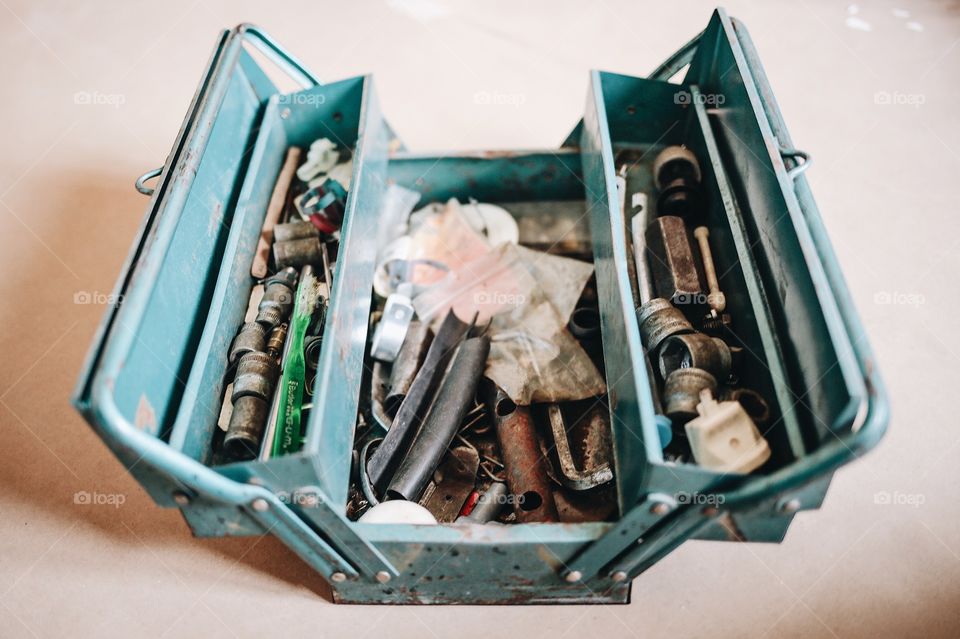 Turquoise Metal toolbox standing on the floor indoors with all kinds of stuff in it 