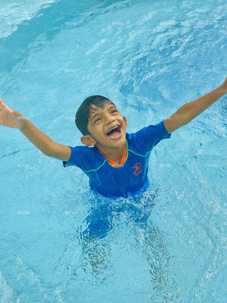 Kid having fun at outdoor swimming pool at summer time 