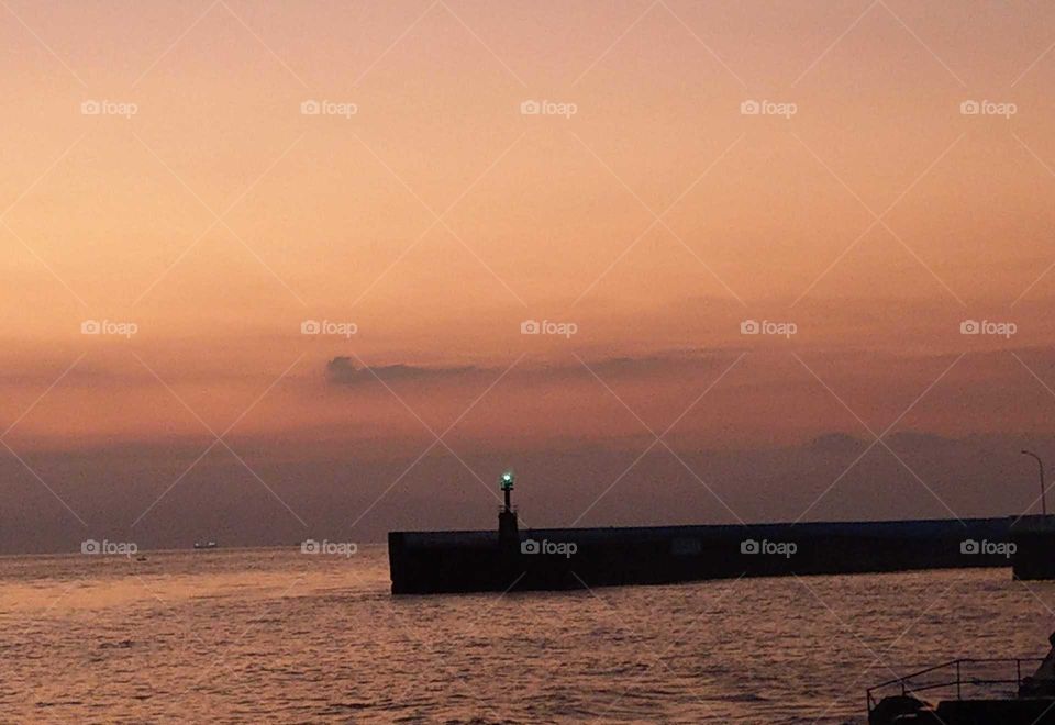 Light: natural Vs artificial. a lighthouse on the island at dawn.