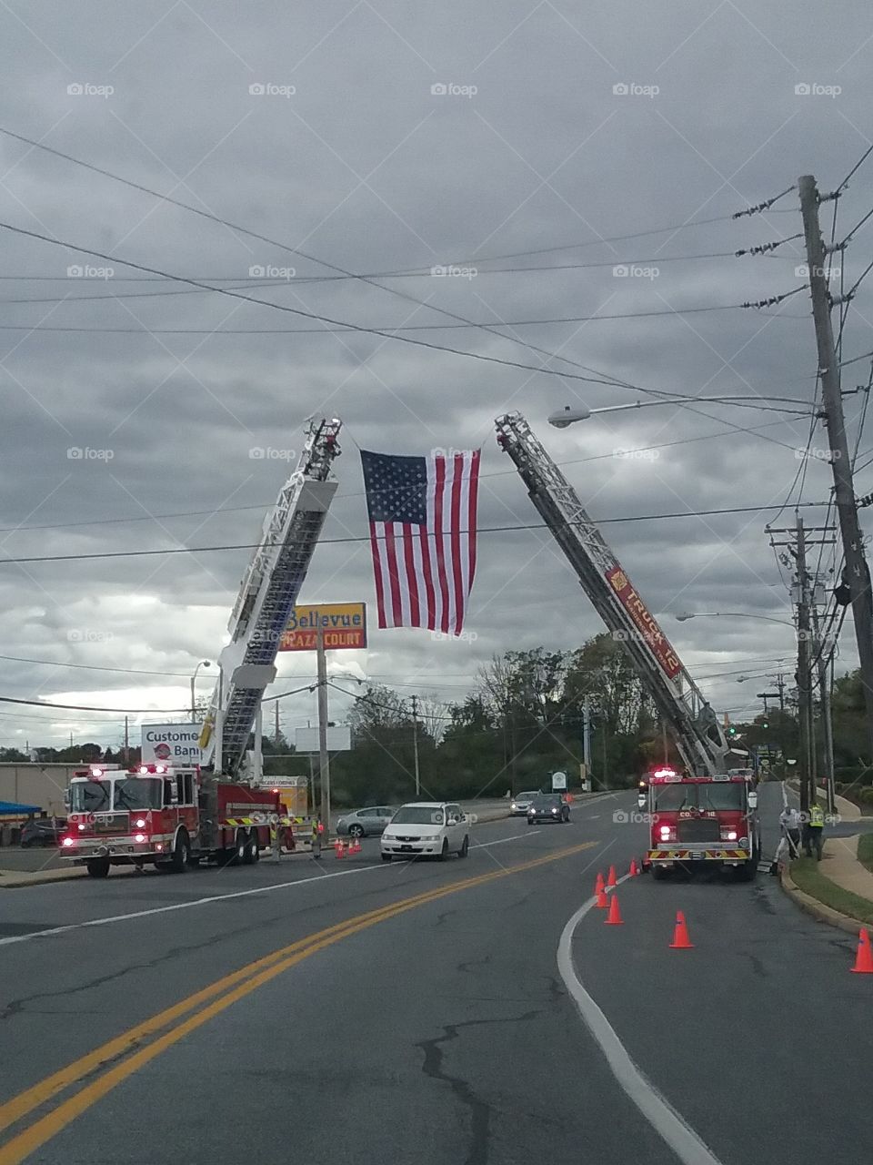 Firetrucks hanging American Flag in street