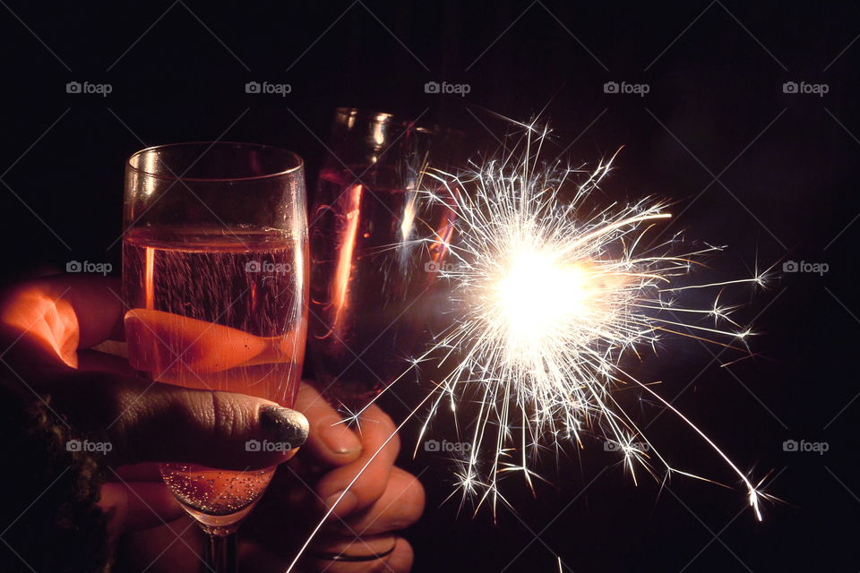 Close-up of hand holding beer glasses with fireworks