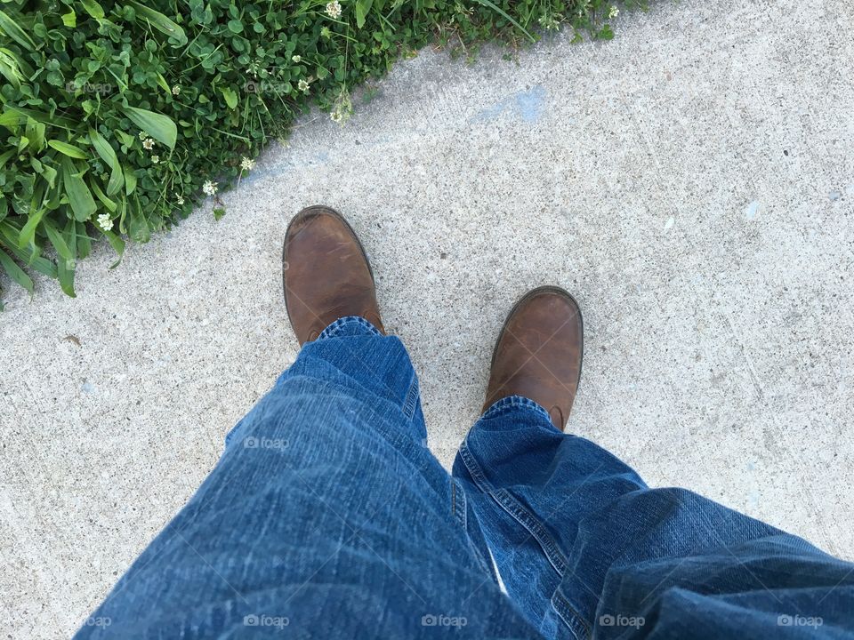 POV legs in jeans with brown leather boots on sidewalk