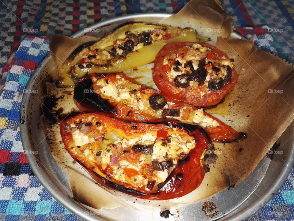 backed red and green stuffed pepper and tomato with olives, onions, fresh tomato and feta cheese