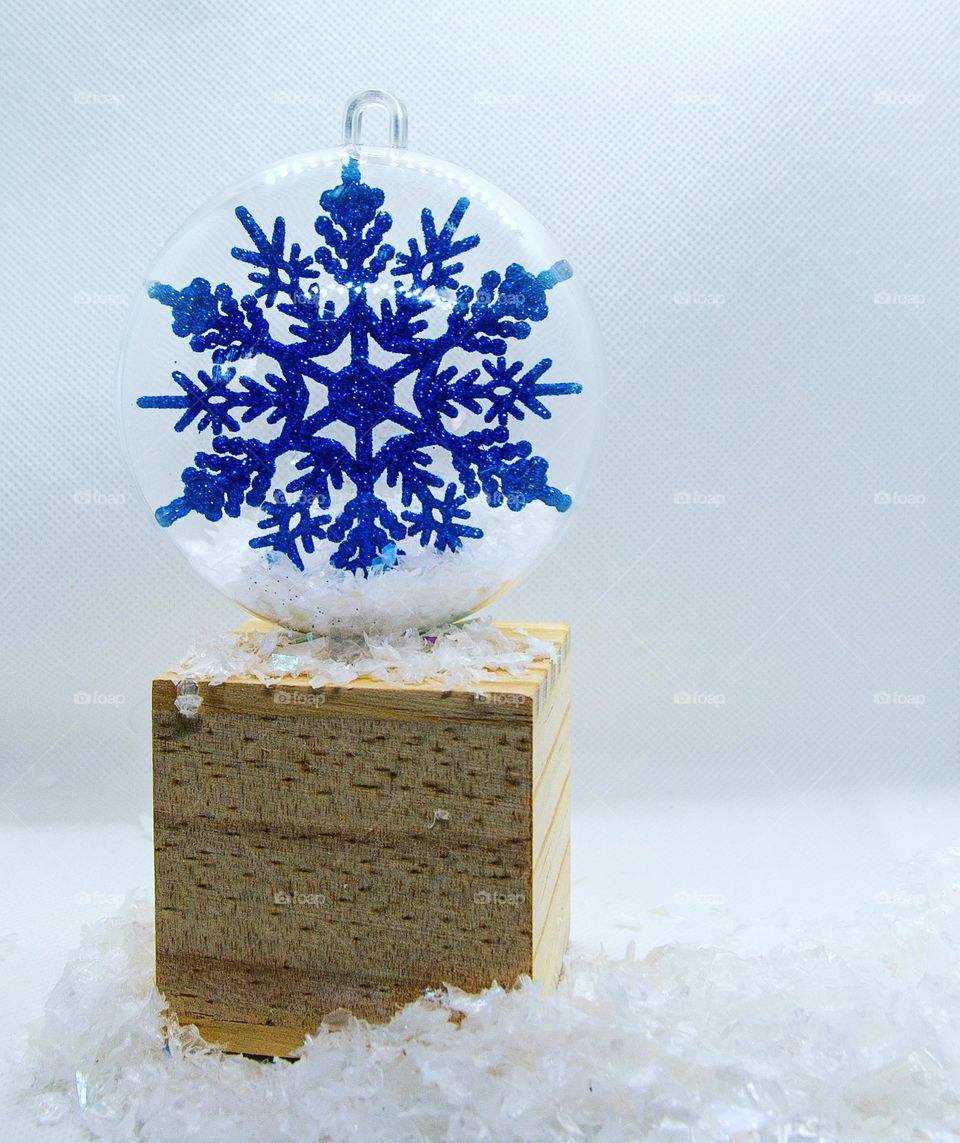 A blue snowflake inside an ornament with artificial snow