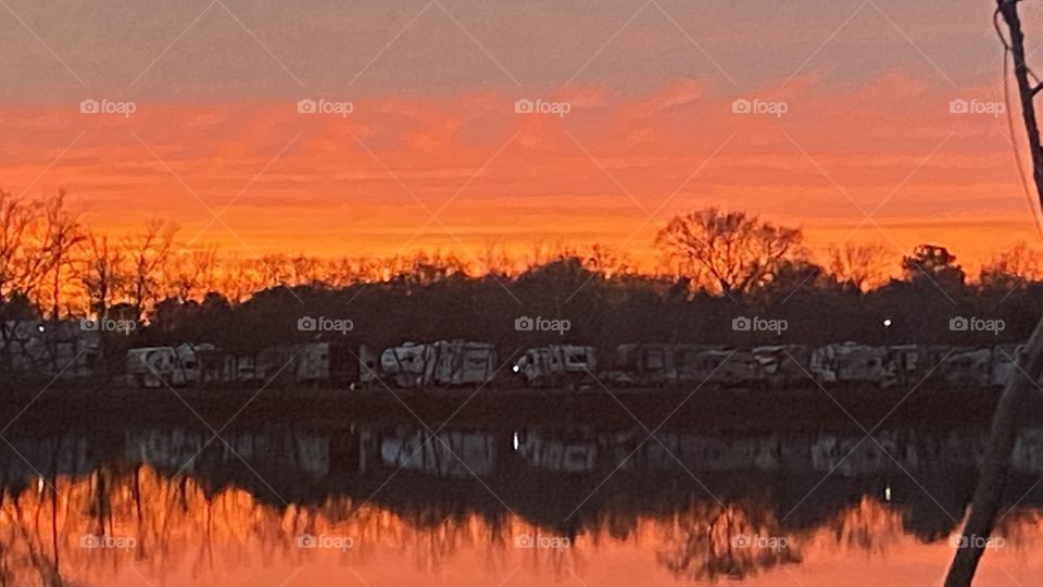 Red Sky At Night Sailors Delight. Sunlit Twilight Reds, Yellows, Oranges Streaking Across The Lower Sky. Total reflections of shore line trees and Lake Waters.