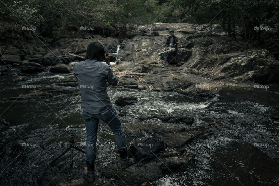 Man talking a photo of the friend in waterfall 