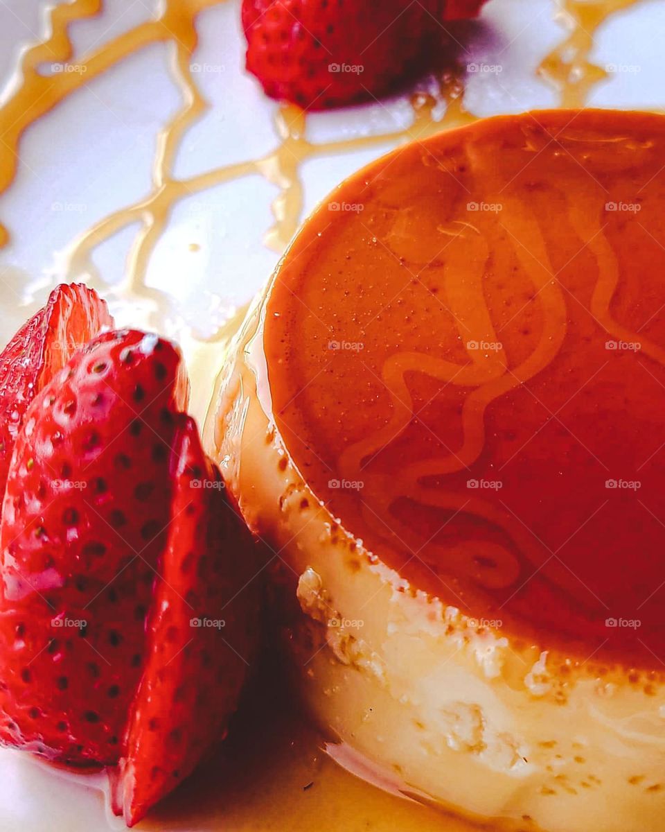 Flan with strawberries and caramel sauce on a white plate 