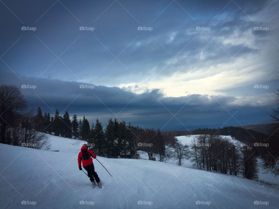 Skier on the slope with grey storm clouds above