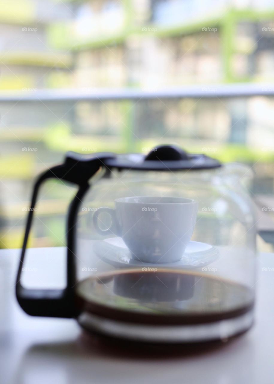 delicious coffee in a teapot and a white cup on the background, morning in the apartment