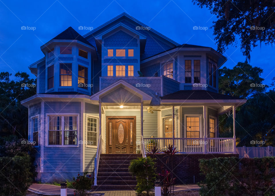 modern Victorian style house with warm interior lights and a cool deep blue night sky