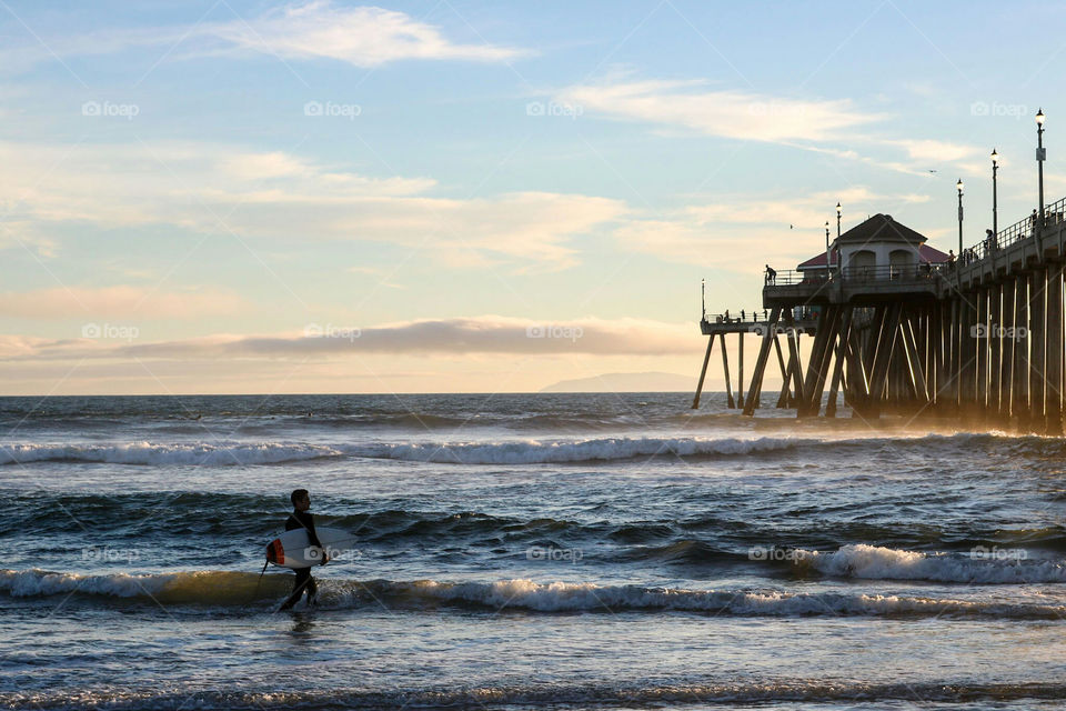 Surfer heading in at Sunset.  Huntington Beach Pier, Huntington Beach, CA.