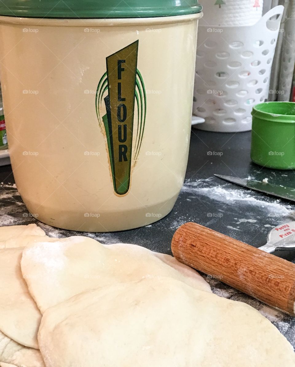 Rolling out the dough for homemade pita bread, vintage 1940s flour canister bin in background. 