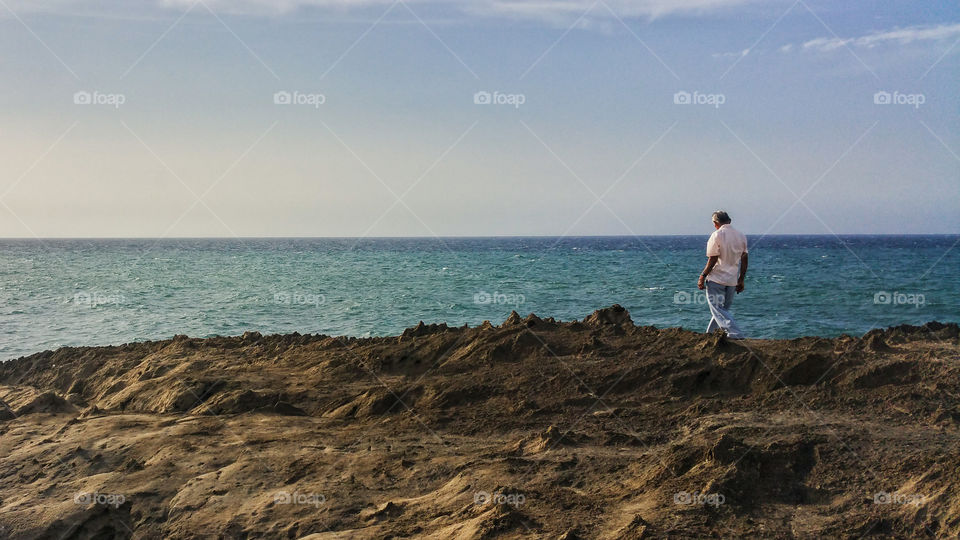 old man walking over the rocks