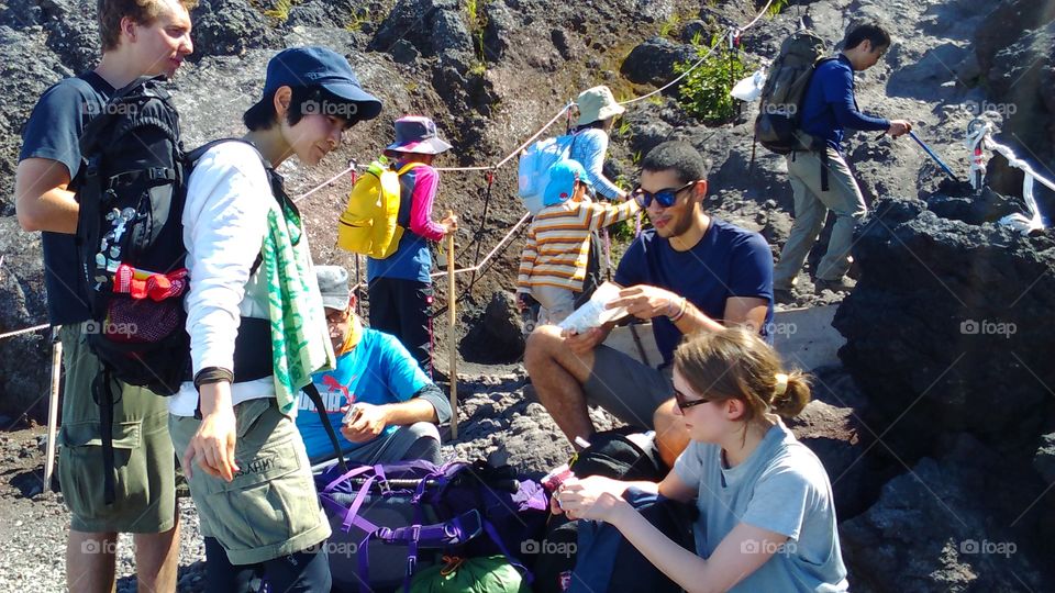 A group of friends stops to rest and eat while climbing Japan's most famous natural landmark, Mount Fuji.