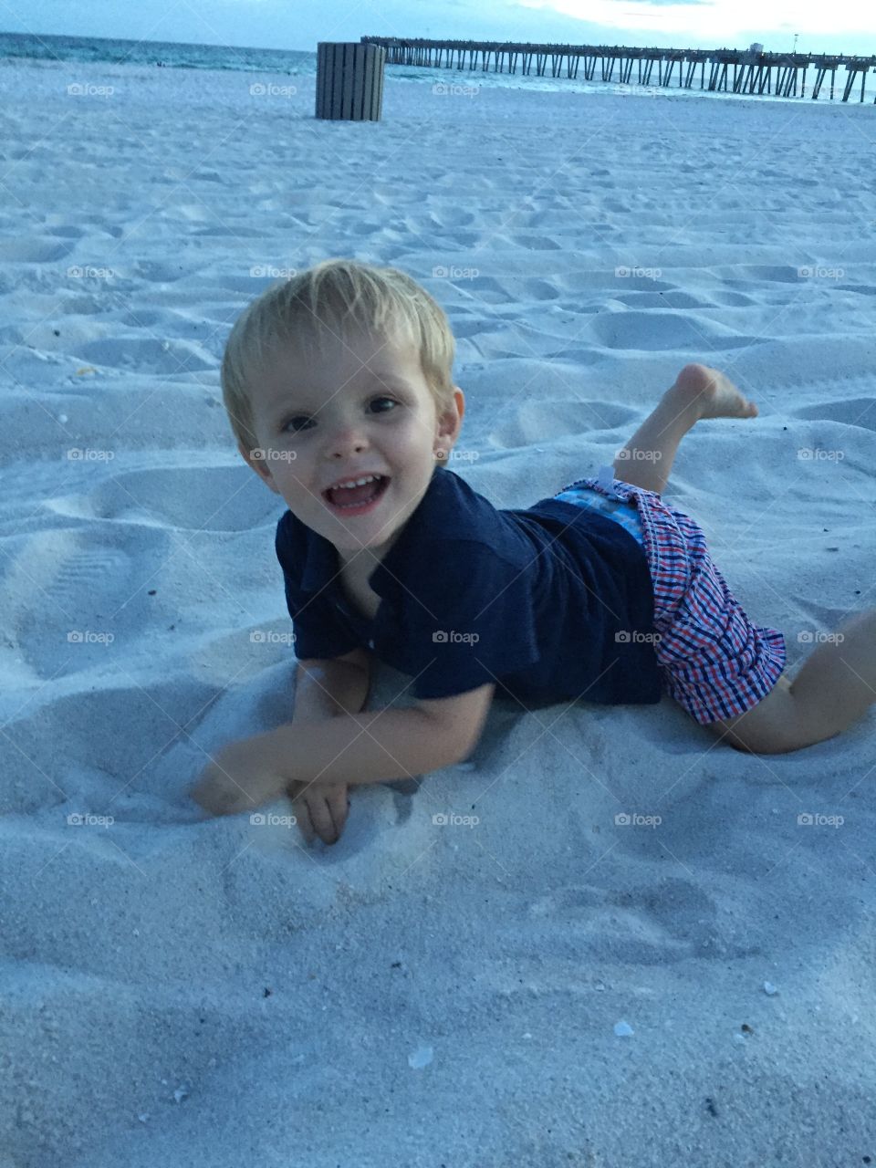 Small boy lying on sand at beach