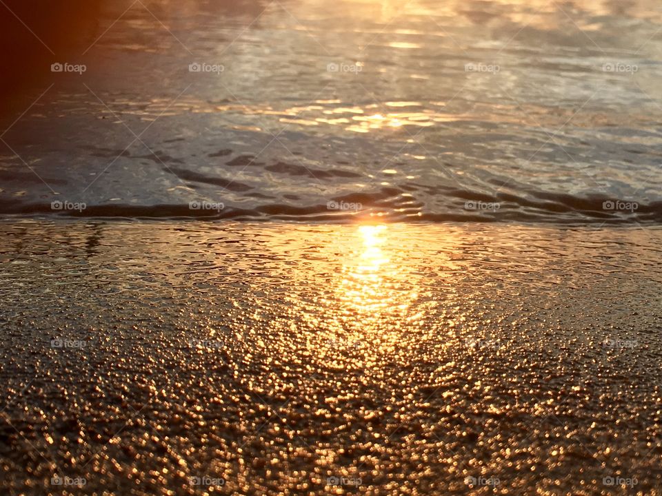 Sunset glow on the lake as water laps onto its sandy shore, Chateaugay Lake in the Adirondack mountains 