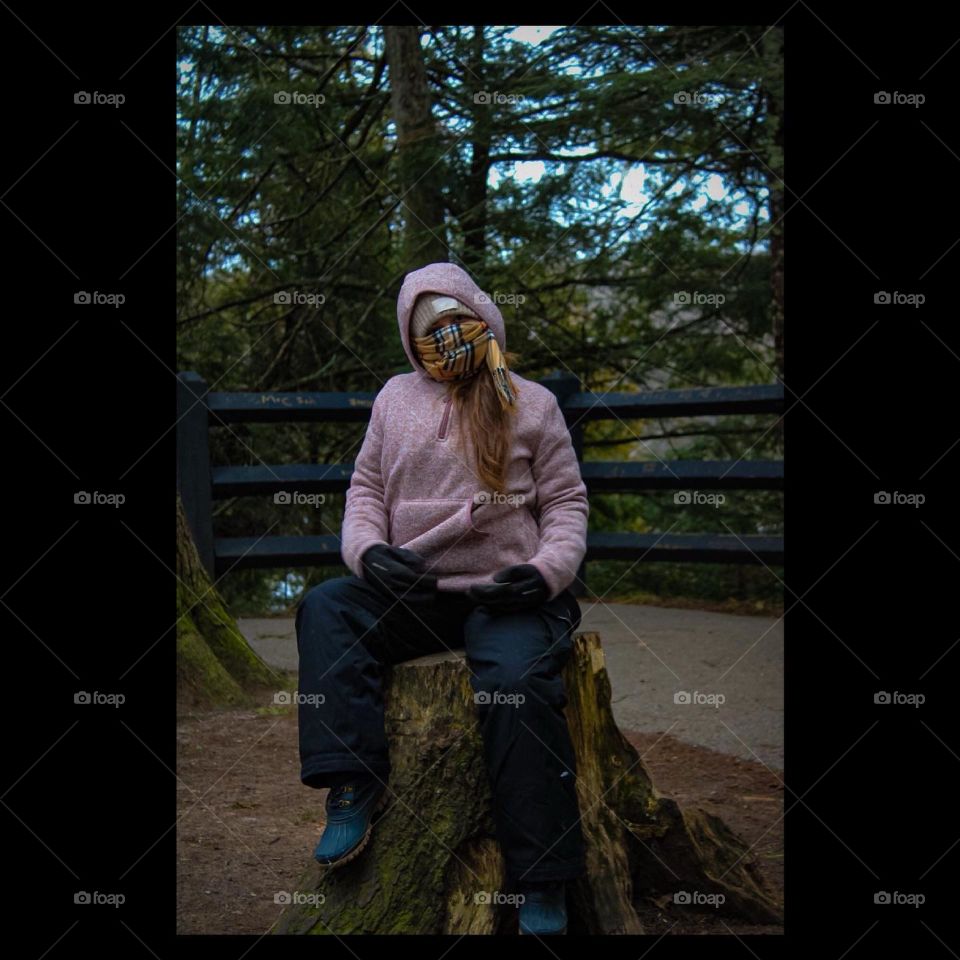 Lost cold, camper sitting on log 