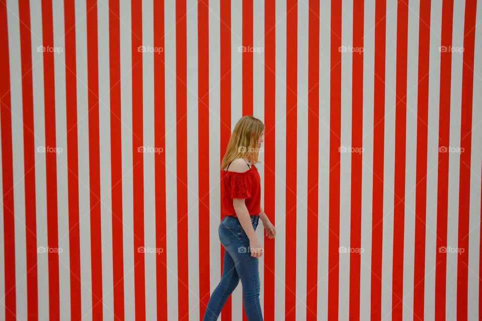 Girl walking in front of red striped wall