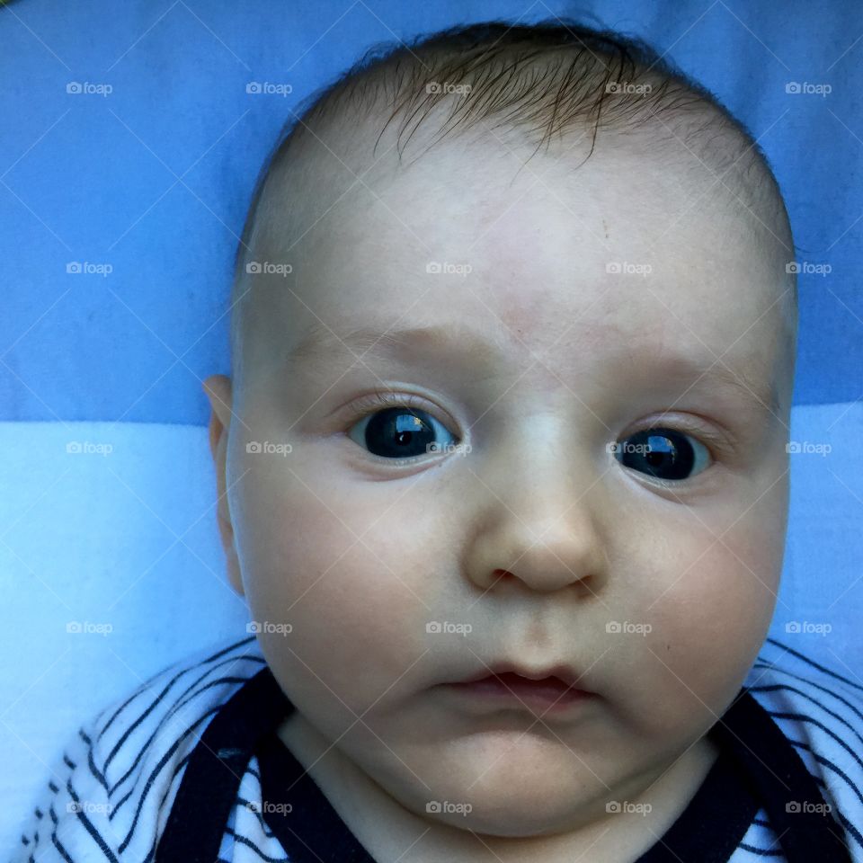 High angle view of baby boy face lying on bed