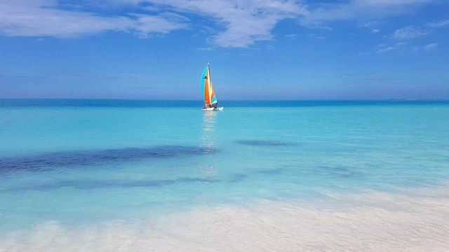A sailboat on the ocean. Turquoise water and blue sky